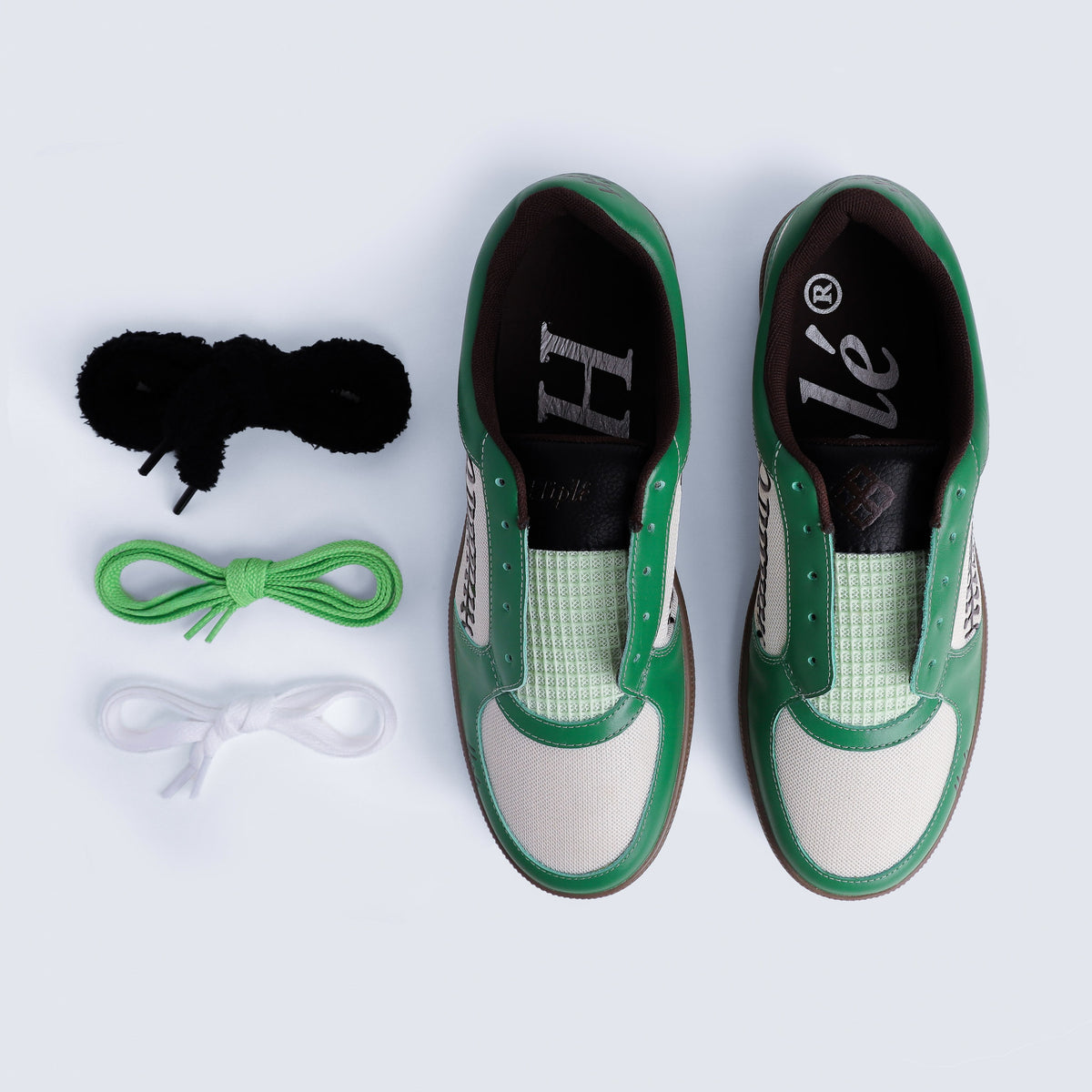 An Ariel view of the ayas sneakers by hiplé
arranged next to three pairs of shoelaces in black, green, and white on a light gray background. (The sneakers are in their SB Green Colorway)
