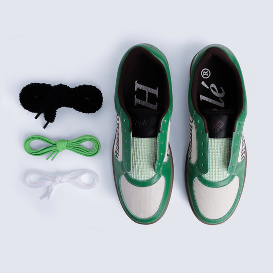 An Ariel view of the ayas sneakers by hiplé
arranged next to three pairs of shoelaces in black, green, and white on a light gray background. (The sneakers are in their SB Green Colorway)