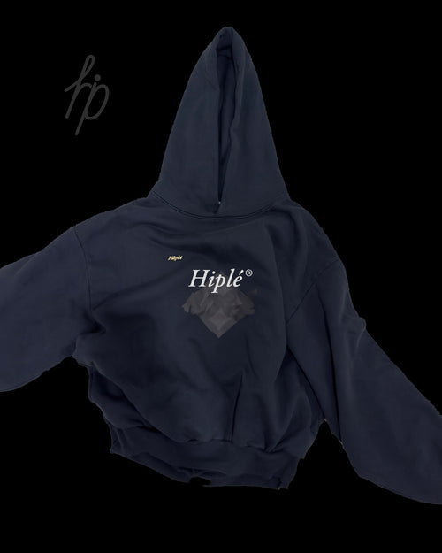 A black garment dye hoodie with a graphic on the chest featuring the text 'Hiple' in white script displayed against a solid black background. 