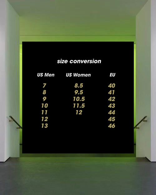 A black wall-mounted size conversion chart with white and yellow text showing US Men, US Women, and EU size mappings, displayed in a modern hallway with green ambient lighting.